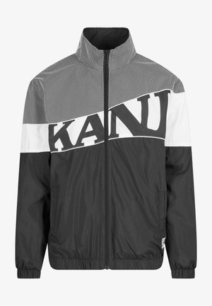 Sort og hvid zip-up jakke med et mesh-mønster, iøjnefaldende bogstaver, høj krave og elastiske manchetter med en glat overflade.