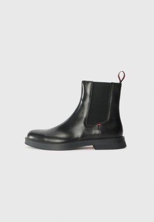 Stivale Chelsea in pelle nera con finitura liscia, pannelli laterali elastici, linguetta e suola in gomma spessa per trazione e durata.