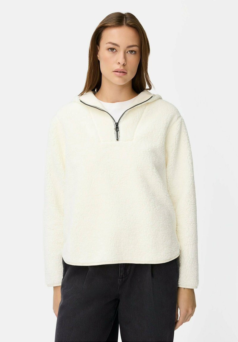 Weißer Fleece-Pullover mit einem Viertel-Reißverschluss-Kragen und strukturierter Oberfläche, ausgestattet mit langen Ärmeln und einem lockeren Schnitt. Getragen mit dunkler Hose.