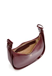 Bordeaux patenten leren tas met een gebogen ontwerp, ritssluiting en beige interieur. Voorzien van gouden hardware en een schouderband.