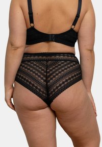 Ensemble de lingerie en dentelle noire comprenant un soutien-gorge avec des bretelles ajustables et une fermeture à crochets, associé à une culotte taille haute avec des motifs géométriques.