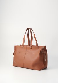 Sac fourre-tout en cuir marron avec double poignées, poche zippée, texture lisse et coutures sur les côtés. Présente un design et une structure minimalistes.