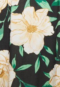 Tissu noir avec de grandes fleurs de pivoine beige et des feuilles vertes. Les fleurs présentent des lignes détaillées et une texture, créant un motif floral vibrant.