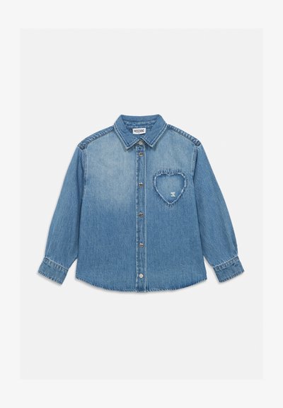 Chemise en denim bleu clair à boutons avec manches longues et un patch en forme de cœur effiloché sur la poitrine gauche.