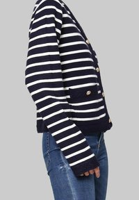 Cardigan rayé bleu marine et blanc avec une texture côtelée, doté d'une fermeture à boutons, d'une poche et de manches longues.