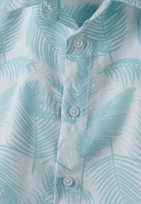Lichtblauw shirt met een palmbladpatroon, voorzien van witte knopen en een zachte textuur. Het ontwerp beschikt over een button-down kraag en gestikte details.