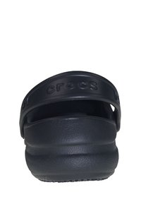 Cizme din cauciuc negre, cu bretele la spate, talpă groasă și suprafață texturată. Numele mărcii "crocs" este gravat pe bretea.