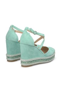 Sandales compensées en daim vert menthe avec design à brides croisées et boucle ajustable. Dotées d'une semelle style espadrille texturée avec garniture décorative.