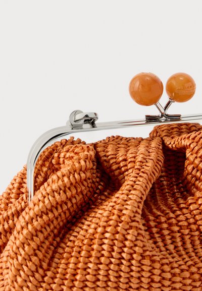 Κοντινό πλάνο πορτοφολιού με πορτοκαλί υφαντή κλειδαριά, ασημένιο μεταλλικό πλαίσιο και δύο στρογγυλά πορτοκαλί κουμπιά κλεισίματος.