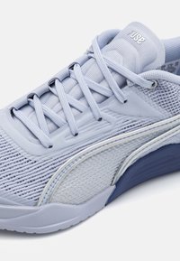 Baskets de sport bleu clair en mesh et matériaux synthétiques. Comprennent des lacets, un design texturé et une semelle bleu foncé avec un accent argenté.