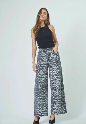 Leopard print wide-leg pants in grey and black, made of denim. Features a high waist and side pockets. Paired with a black sleeveless top.