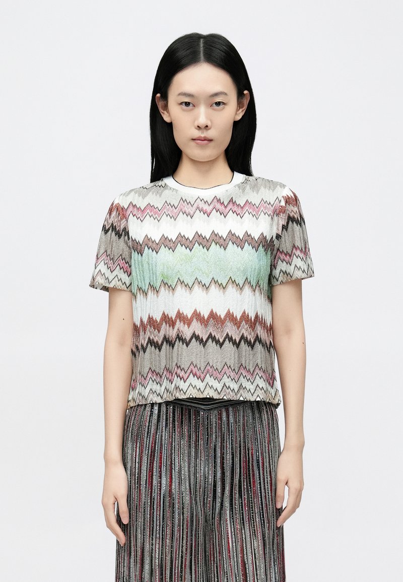 Īsroku krekls ar zigzaga rakstu rozā, zaļā un bēšā toņos. Izgatavots no teksturēta auduma ar apaļu apkakli.