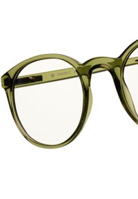 Gröna glasögon med rund ram, transparenta linser och en glänsande finish. Starka bågar har subtila gravyrdetaljer.