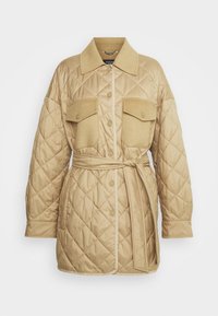 Veste matelassée beige avec col à revers, deux poches poitrine et taille ceinturée. Présente des surpiqûres diagonales et des fermetures à boutons pression.