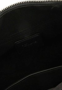Interno di una borsa nera con zip che mostra una finitura opaca, foderatura in tessuto e una piccola tasca con un'etichetta. La zip presenta denti metallici.
