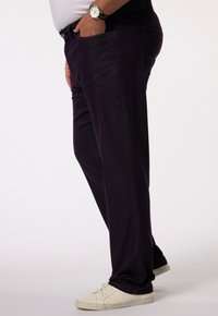 Pantalons droits violet foncé en mélange de coton, dotés de poches latérales et d'une texture lisse. Portés avec des baskets blanches.