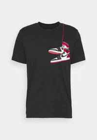 Svart t-shirt med ett tryck av röda och vita sneakers med svarta detaljer på framsidan. Rundhalsad design, tillverkad av mjukt tyg.