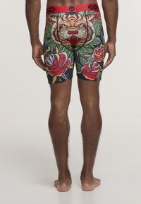 Kolorowe bokserki z wyraźnym nadrukiem tygrysa, kwiatowymi wzorami i czarnym tłem. Wykonane z miękkiego, elastycznego materiału z czerwonym paskiem w talii.