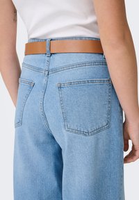 Ljusblå jeans i denim med hög midja, utrustade med ett brunt läderbälte. Märkbara detaljer inkluderar två bakfickor och en rak benmodell.