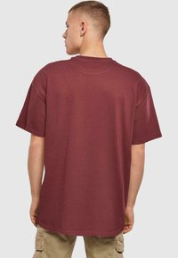 Bordeaux oversized t-shirt lavet af blødt stof. Har korte ærmer, en rund halsudskæring og et enkelt design uden synlige logoer eller mønstre.