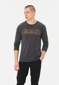 Donkergrijze lange mouw T-shirt met gouden berggraphics op de borst. Zacht materiaal met een ronde hals en een regular fit.