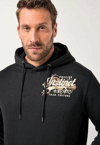 Felpa nera con cappuccio in cotone con cordino. Presenta un logo grafico colorato sul petto, che mostra disegni intricati e testo.