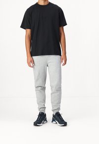 Black cotton t-shirt with a crew neck, paired with light gray jogger pants. Complete with dark sneakers featuring white accents.