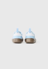 Chaussures de sport bleu et blanc avec une semelle marron texturée, dotées de languettes au niveau des talons et d'un design épuré et minimaliste.
