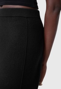 Zwarte gebreide rok met een zachte, gestructureerde uitstraling. Heeft een elastische tailleband en een getailleerd silhouet met zijnaaddetails.