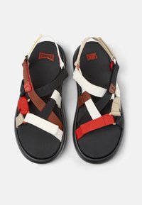 Black sandal with multicolored straps in red, white, brown, and beige. Thick sole; features brand logo "Camper" and "Twins" prominently.