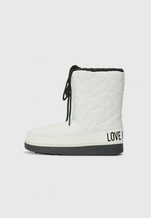White quilted ankle boot with heart pattern, black accents, and a textured sole. Features a branded segment on the heel and black laces.
