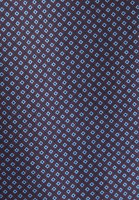 Motif diagonal répétitif de petits losanges bleu clair sur un fond en tissu brun rougeâtre foncé.
