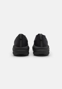 Schwarze Sport Schuhe mit einem schlanken Strick-Obermaterial, strukturierten Akzenten und einer robusten Gummisohle, ausgestattet mit einer Lasche an der Ferse für einfaches Anziehen.