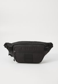 Schwarze strukturierte Bauchtasche mit zwei Reißverschlussfächern und verstellbaren Seitenträgern, ausgestattet mit einem quadratischen Patch mit eingeprägtem Markennamen.