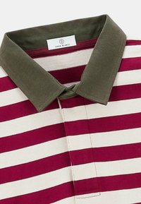 Polo rayé présentant des rayures horizontales bordeaux et crème, avec un col vert olive uni et une étiquette portant la mention "SERGE BLANCO."