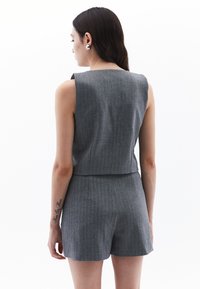 Top corto grigio senza maniche con tessuto texturizzato e design dritto, abbinato a pantaloni corti a vita alta coordinati.