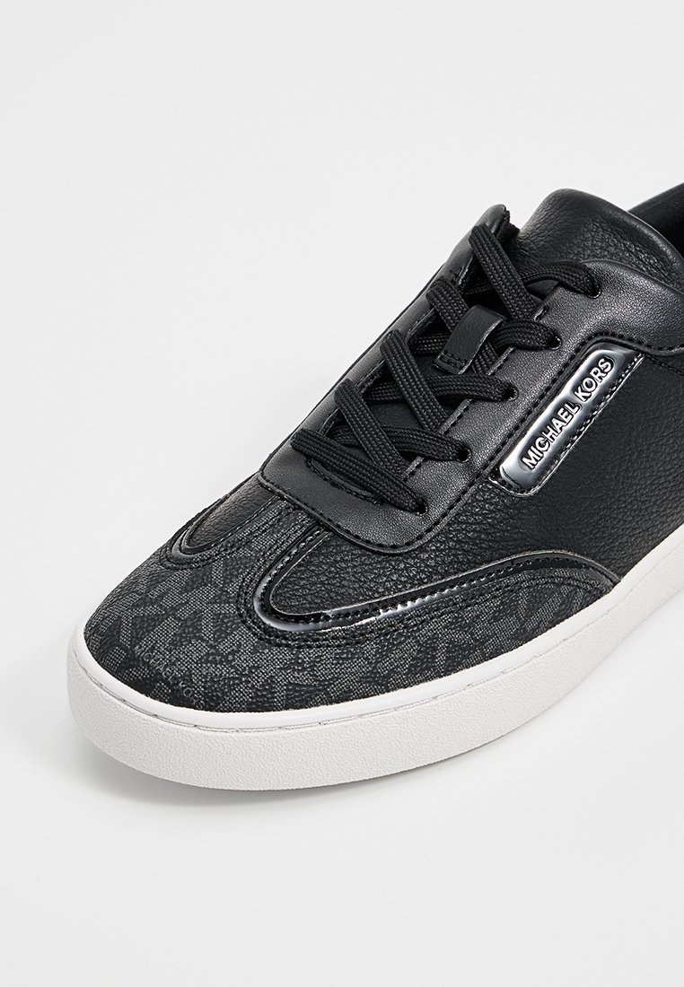 Sneaker noir avec tige en cuir texturé et motif tissé, doté d'une semelle en caoutchouc blanc, d'un design à lacets noir et d'un accent logo.