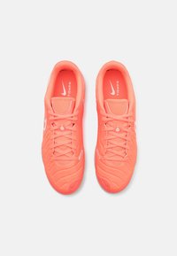 Tenisky Nike Tiempo v jasném korálovém odstínu, vyrobené z texturovaného syntetického materiálu, s designem na šněrování a lehkou podešví.