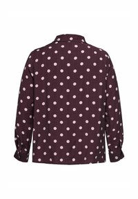 Donkerpaarse blouse met lange mouwen, lichtroze polkadots, knoopmanchetten en een klassieke kraag, gezien van achteren.