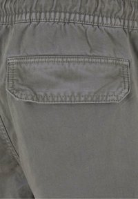 Szare bawełniane spodnie z elastycznym pasem, wyposażone w jedną naszywaną kieszeń z tyłu z przeszyciami oraz ukośnym szwem.