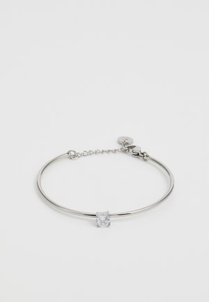 Bracciale rigido in metallo argentato con una pietra quadrata trasparente al centro, dotato di una delicata catena e chiusura per la regolazione.