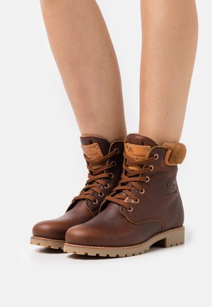 Brązowe skórzane botki za kostkę z wyściełanym kołnierzem, sznurówkami i solidną podeszwą. Posiadają naszywkę z logo oraz widoczne akcenty ściegów.