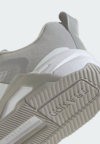 Šedá sportovní obuv s texturovaným svrškem, hladkými akcenty a vzorovanou gumovou podešví. Obsahuje zesílenou patu a detaily s logem.