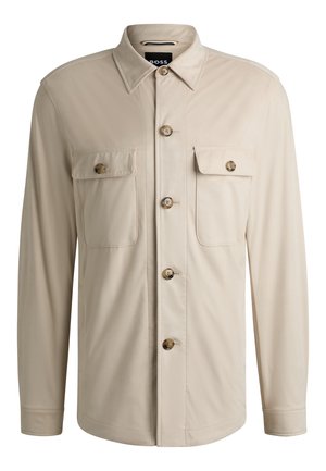 Beige button-up shirt with a collar, two chest pockets, and brown buttons. Smooth fabric with a slightly structured shape.