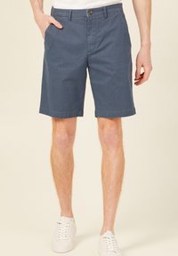 Marinblå bomullsshorts med rak front, sidofickor och en enda knappstängning. Avslutade vid knäet med en strukturerad yta.