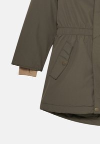 Giacca isolata verde oliva con vita elasticizzata e dettagli in beige sulle maniche. Presenta una tasca laterale con chiusura a scatto.