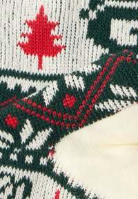 Πλεκτό πουλόβερ με κρέμ βάση και κόκκινο μοτίβο φύλλου σφενδάμου, σκούρες πράσινες λεπτομέρειες και υφή. Τα πλαίσια έχουν κόκκινες και λευκές λεπτομέρειες.