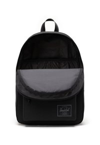 Sac à dos noir avec un intérieur rayé gris et une poche avant. Il dispose d'une poignée supérieure, d'une fermeture à rabat et d'une étiquette de marque sur le devant.