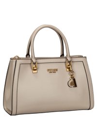 Sac à main Guess beige avec poignées supérieures doubles, quincaillerie dorée, logo de la marque et charme décoratif doré suspendu à l'avant.