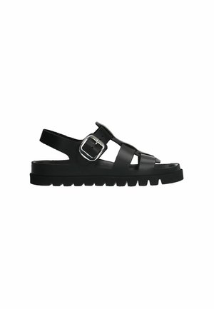 Black sandals made of synthetic material featuring a buckle, open design, and thick, textured sole with a ribbed pattern.